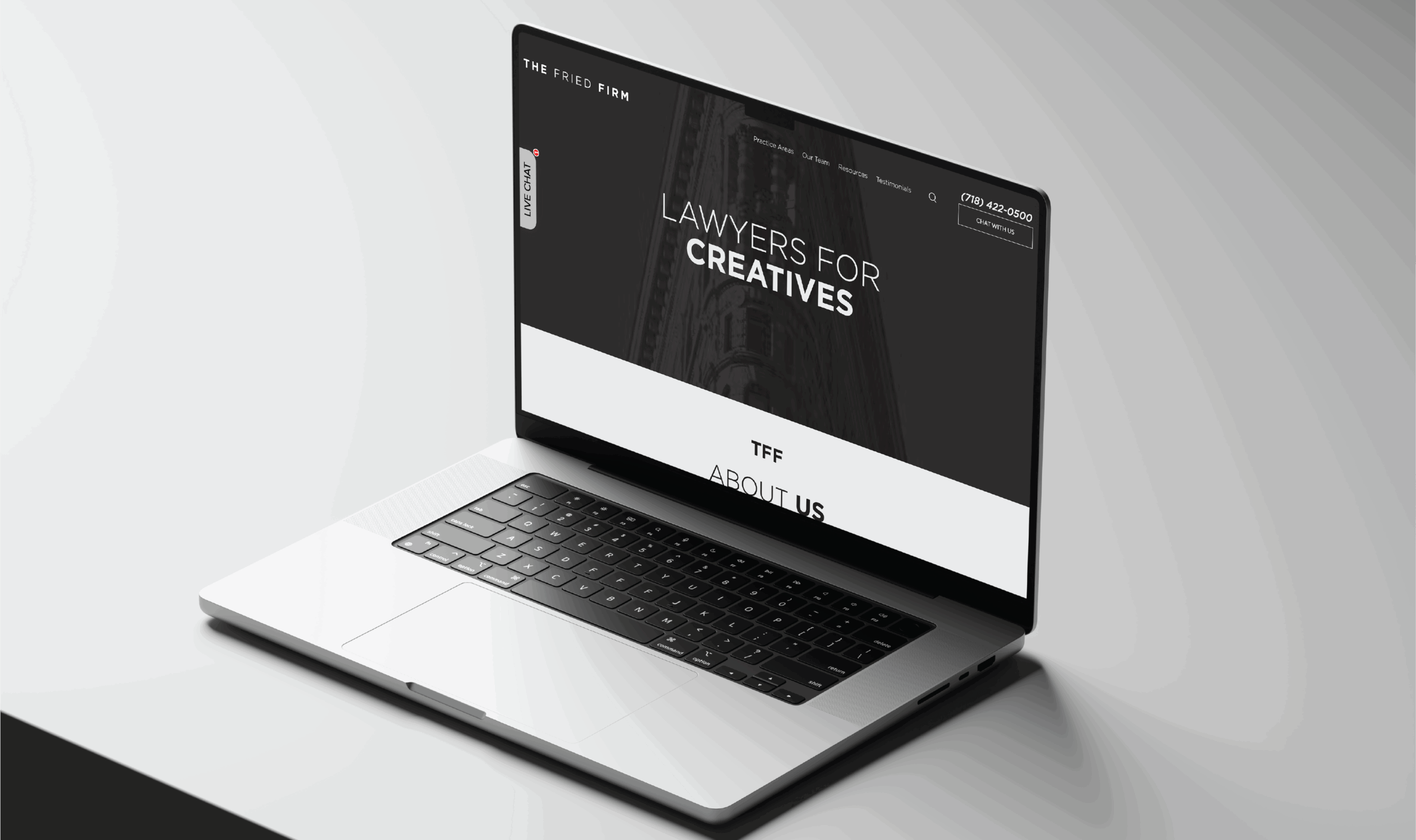 A sleek laptop on a white surface displays a website with the text LAWYERS FOR CREATIVES in bold letters, along with contact information and navigation links on the screen.