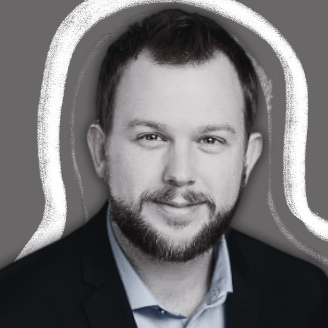 A man with short dark hair and a beard, wearing a dark blazer and light-colored shirt, is smiling slightly. The background is gray with white, curved lines drawn around his head and shoulders.