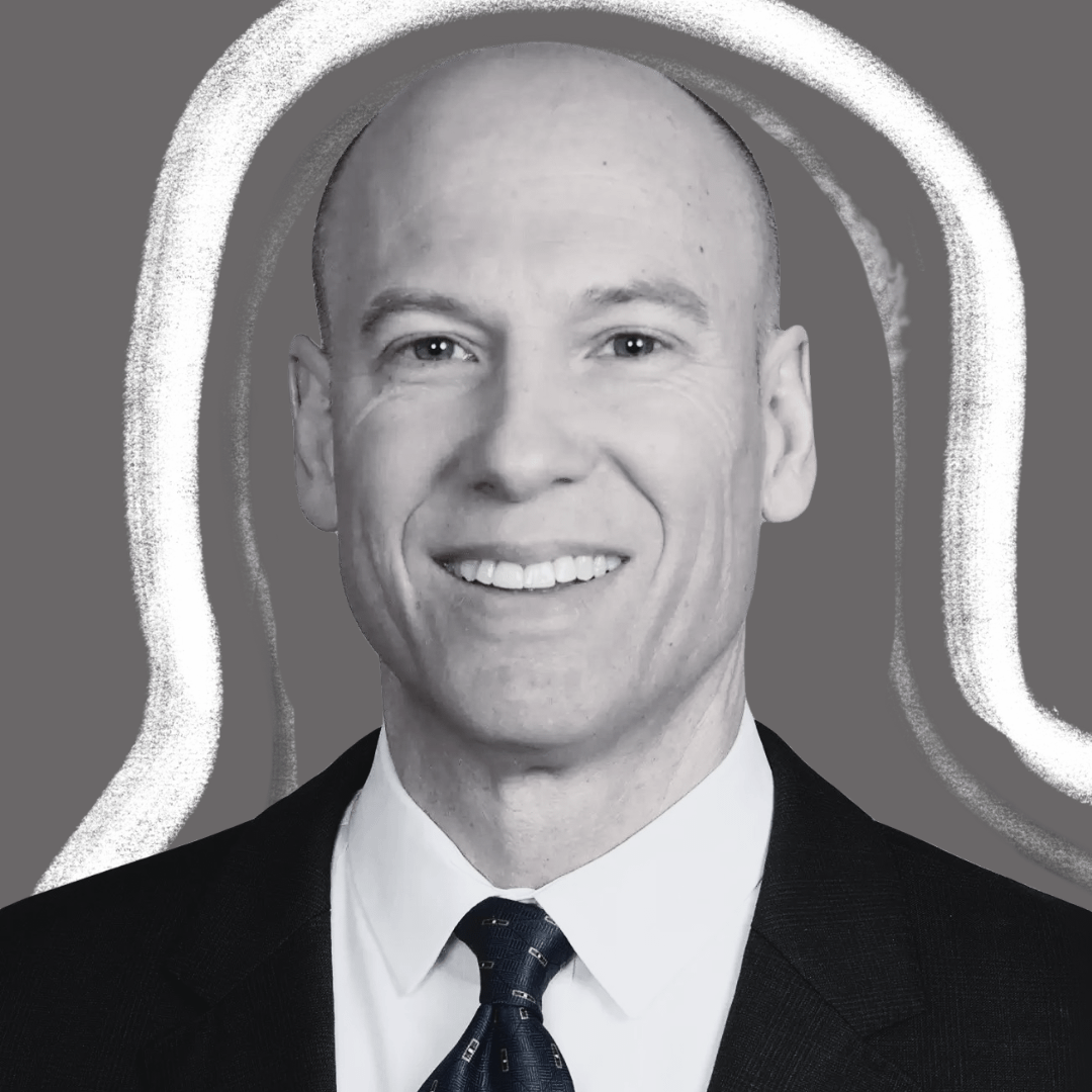 A smiling, bald man in a suit and tie is centered against a gray background with abstract white lines outlining his head and shoulders.