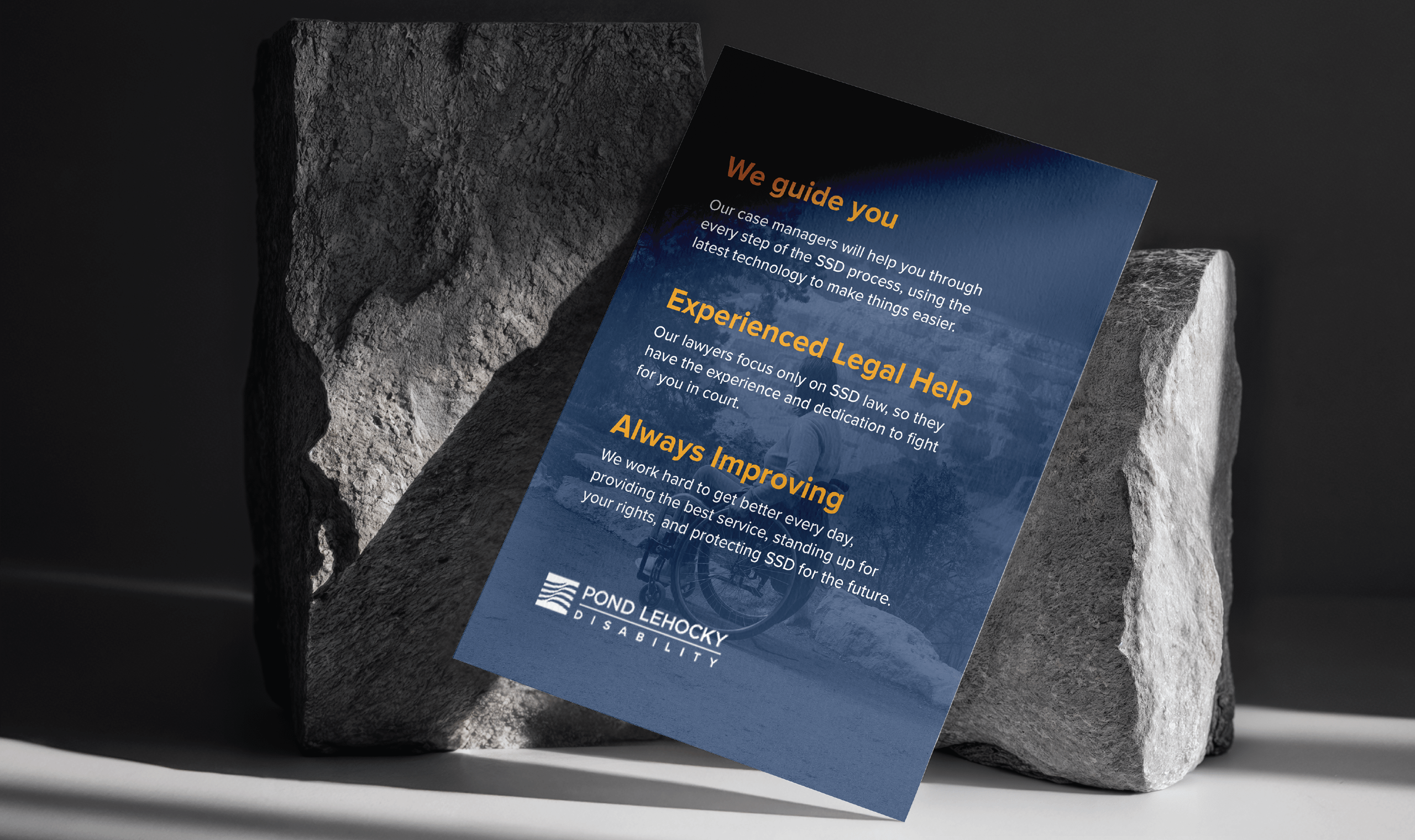 A flyer with text about legal assistance rests against two large gray stones. It features keywords like 