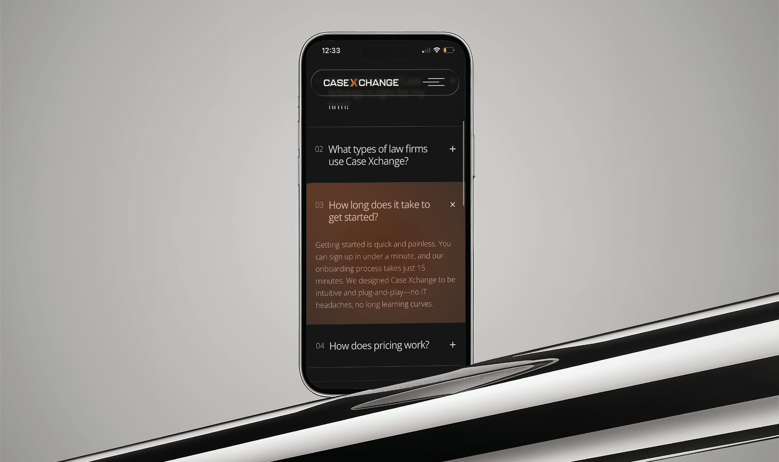 Smartphone displaying the Case Xchange mobile website with an FAQ section visible. The screen shows questions such as “What types of law firms use Case Xchange?” and an expanded answer under “How long does it take to get started?” The phone rests on a reflective black-and-white curved surface against a neutral gray background.