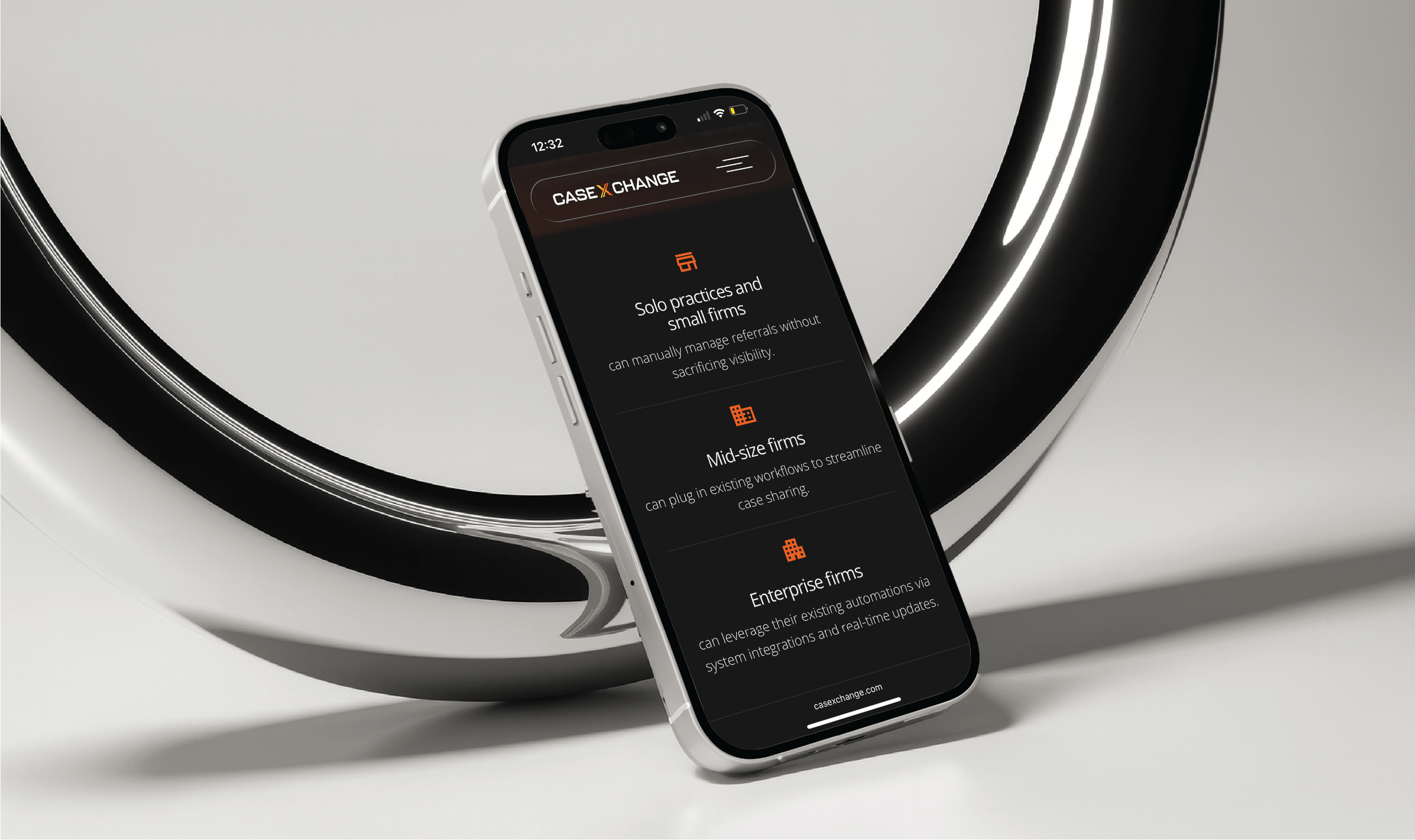 Smartphone displaying the Case Xchange mobile website with sections for different firm types: solo and small firms, mid-size firms, and enterprise firms. The phone leans against a reflective circular black-and-white metallic structure on a light gray surface.